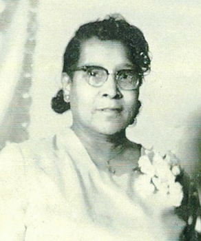 Black and white photo of a woman wearing glasses and a floral dress.