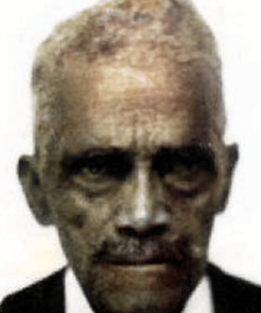 A close-up of an elderly person with short, gray hair and a mustache.